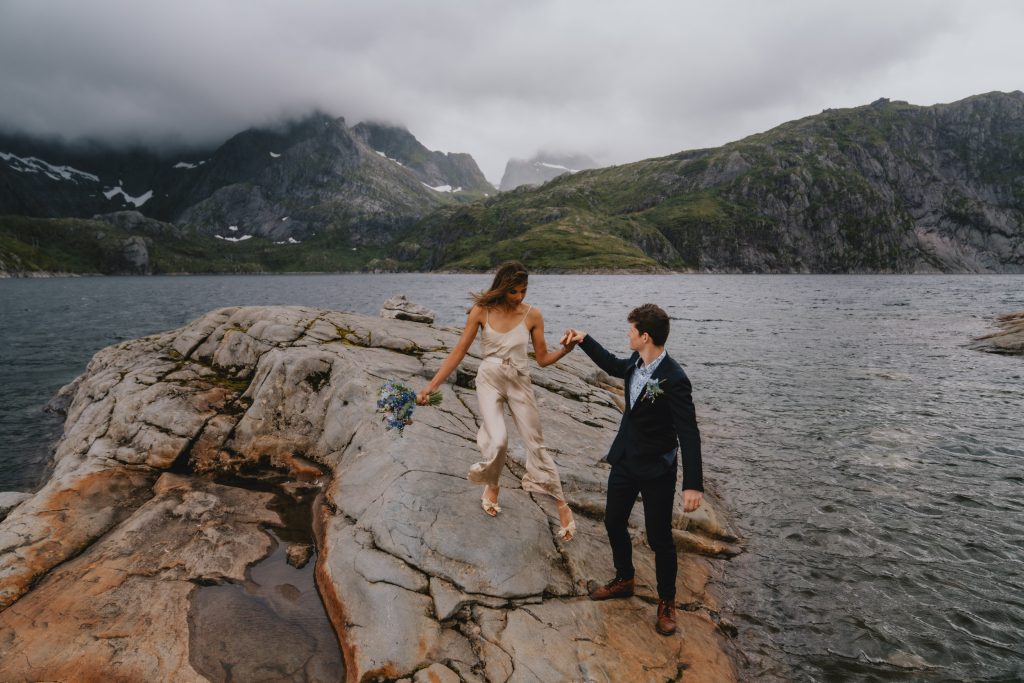 How to choose your elopement photographer. Giving a helping hand to his bride after the ceremony in moody Lofoten. By Christin Eide Photography